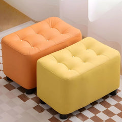 The ottoman stool silhouette features softly rounded corners and a sturdy build supported by short cylindrical legs.