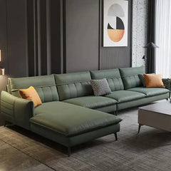 Green sectional sofa in a modern living room with abstract art on the wall.