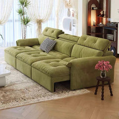 Green sectional sofa in a living room with a small table and flowers.