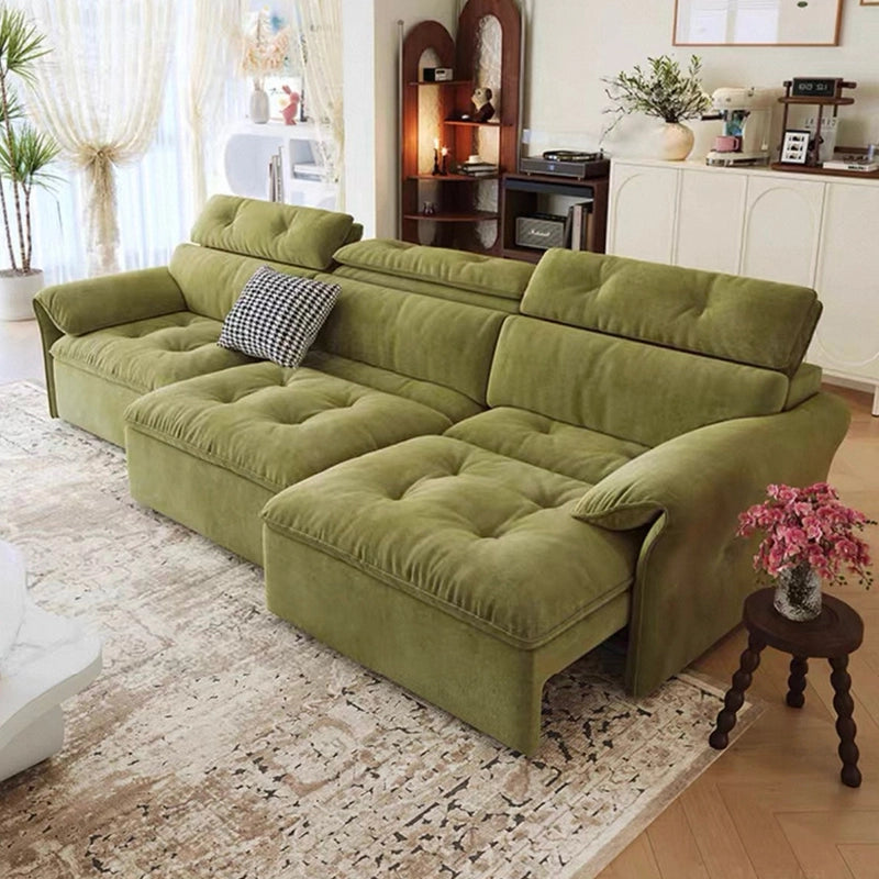 Green sectional sofa in a living room setting with decor elements.
