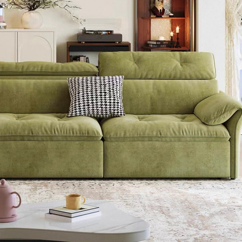 Green sofa with a patterned pillow in a living room setting
