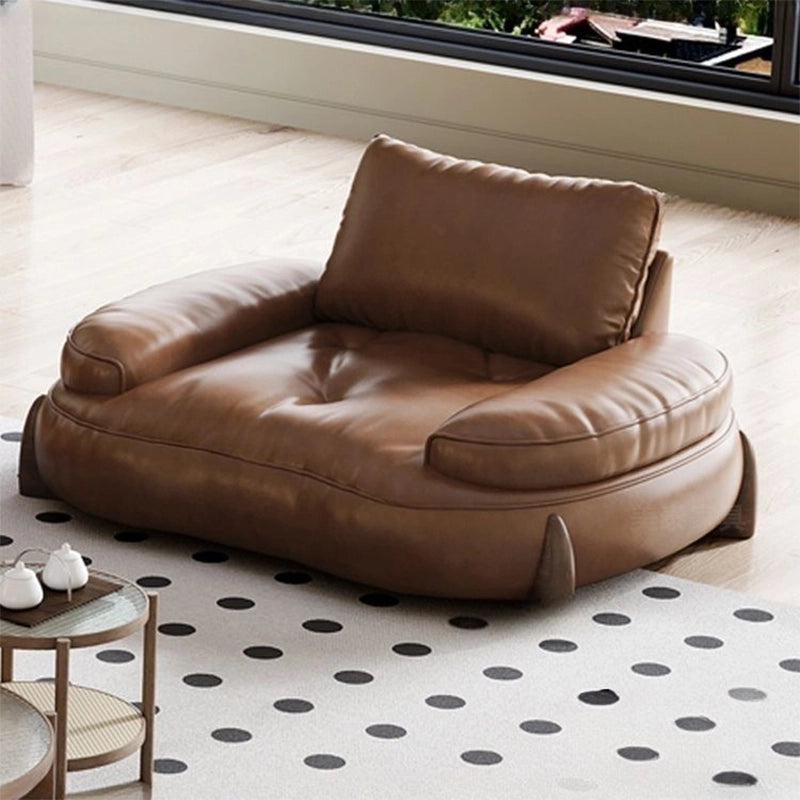 Short, rounded wood legs anchor its relaxed presence. The pure leather surface offers durability and ease, ideal for families and pet owners.