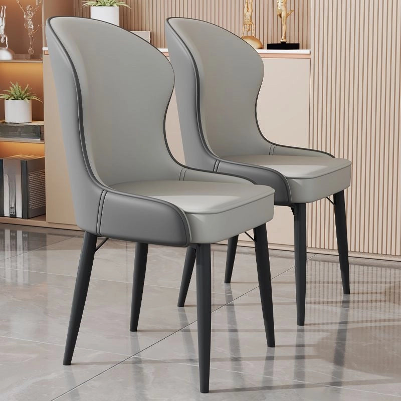 These modern dining chairs feature a sculpted wingback silhouette, soft faux leather upholstery in chic colour options, and slim tapered black metal legs for a clean, contemporary look. 