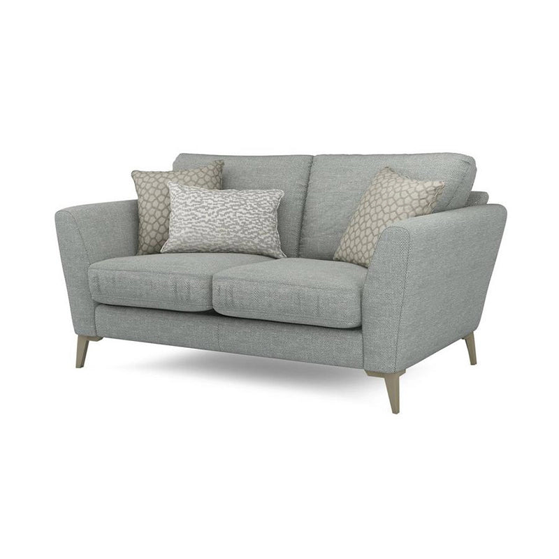 Tapered legs in wood and metal finishes elevate its visual lightness while plush cushions ensure ergonomic comfort.