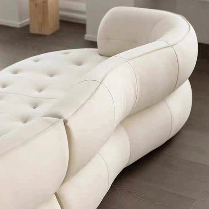 The hidden legs, deep seat base, and seamless contours create a grounded silhouette, while the mid-back tufted cushions provide support.