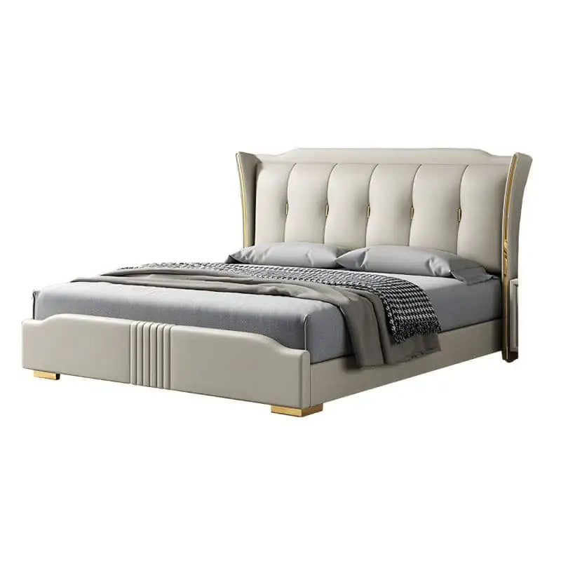 Its tall, channel-tufted wingback headboard in cream leatherette is paired with gold trim edges and low metallic feet that add refined warmth to any master bedroom.