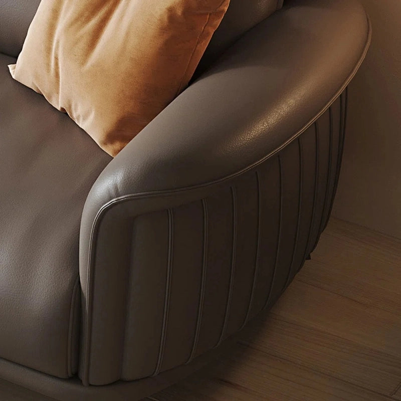Brown leather sofa with a cushion on a wooden floor