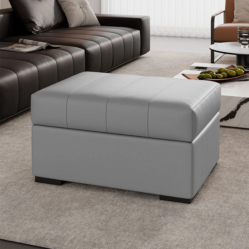 Its firm cushioned top acts as a footrest or compact seat, while the hinged lid opens to reveal ample inner storage.