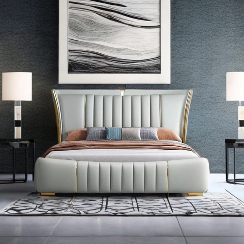 Its sculpted silhouette features a tall, wingback headboard with vertical channel tufting and quilted side wings, upholstered in smooth leatherette available in grey, camel, sage, or white. 

