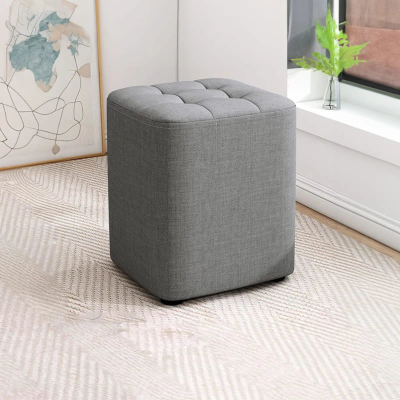 Gray ottoman in a room with a rug and wall art